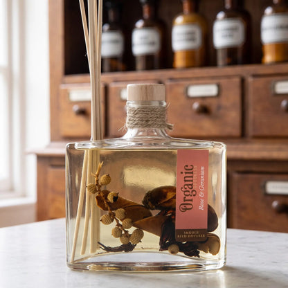 Flaschenhals des Reed Diffusers Rose und Geranie aus der Nähe: Holzstopfen, Jutekordel, Schilfrohrstäbchen und die Hölzer und Beeren im Öl