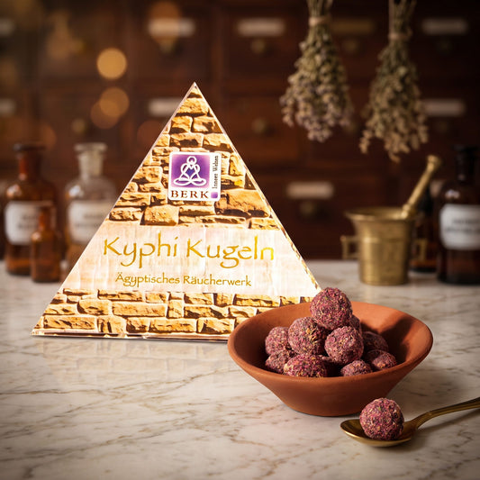 Kyphi Kugeln von Berk: die Pyramidenverpackung auf der Marmortheke einer alten Apotheke am Abend, daneben eine Terracottaschale mit rosafarbenen Kyphi-Kugeln und ein Messinglöffel – Spirit of Gaia