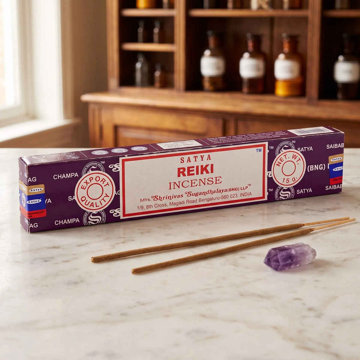 Satya Reiki Räucherstäbchen: 15-g-Packung auf einer Marmortheke vor einem Apothekerschrank, daneben zwei lose Räucherstäbchen – Spirit of Gaia