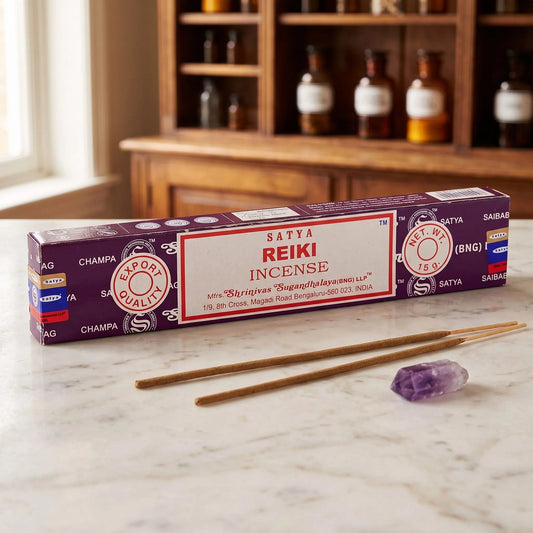 Satya Reiki Räucherstäbchen: 15-g-Packung auf einer Marmortheke vor einem Apothekerschrank, daneben zwei lose Räucherstäbchen – Spirit of Gaia