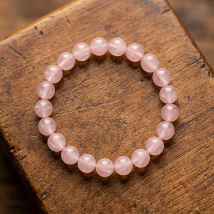 Makro der naturbelassenen, milchig-rosa Rosenquarz-Perlen des Edelstein-Kugelarmbands