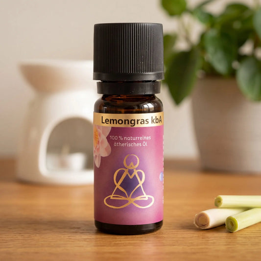 Ätherisches Öl Lemongras: Fläschchen auf einem Holz-Sideboard im Wohnzimmer, im Hintergrund eine weiße Duftlampe, daneben Zitronengras