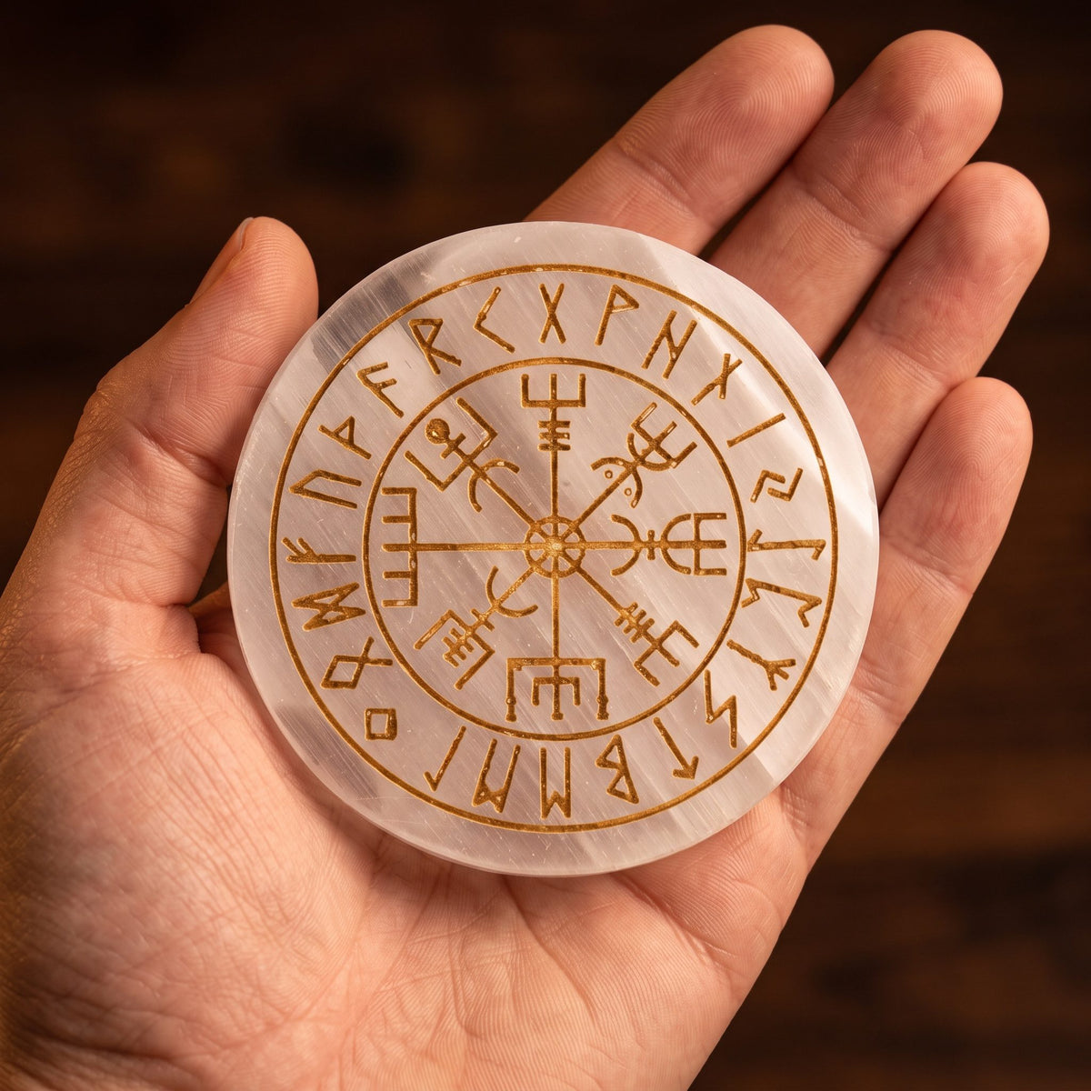 Eine Hand hält die Vegvisir-Platte aus Selenit, so wird ihre Größe von 7 cm sichtbar