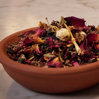 Liebesräucherung, Räuchermischung der Reihe Einfach Räuchern von Berk, 50 ml im Korkglas: Nahaufnahme der Terracottaschale mit Rosenblüten, einer Rosenknospe und dunklen Stücken vor der warmen, unscharfen Abendapotheke – Spirit of Gaia
