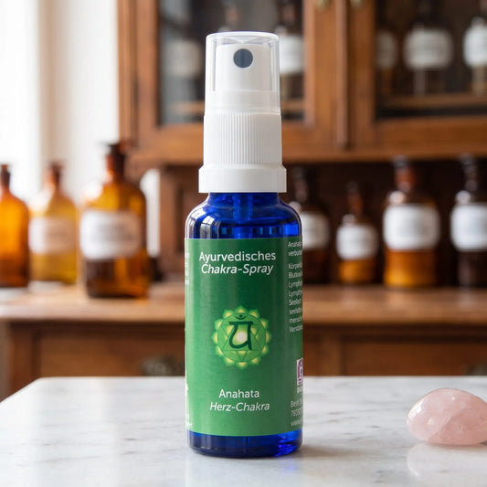 Ayurvedisches Chakra-Spray Anahata (Herz-Chakra): 30-ml-Sprühflasche aus blauem Glas auf Marmortheke vor Apothekerschrank, daneben Rosenquarz – Spirit of Gaia