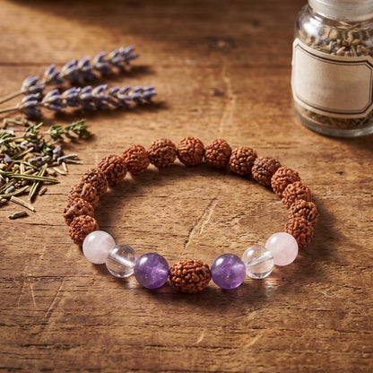 Rudraksha Armband mit Edelsteinen auf einem Holztisch neben Lavendel und einem Glas mit Kräutern