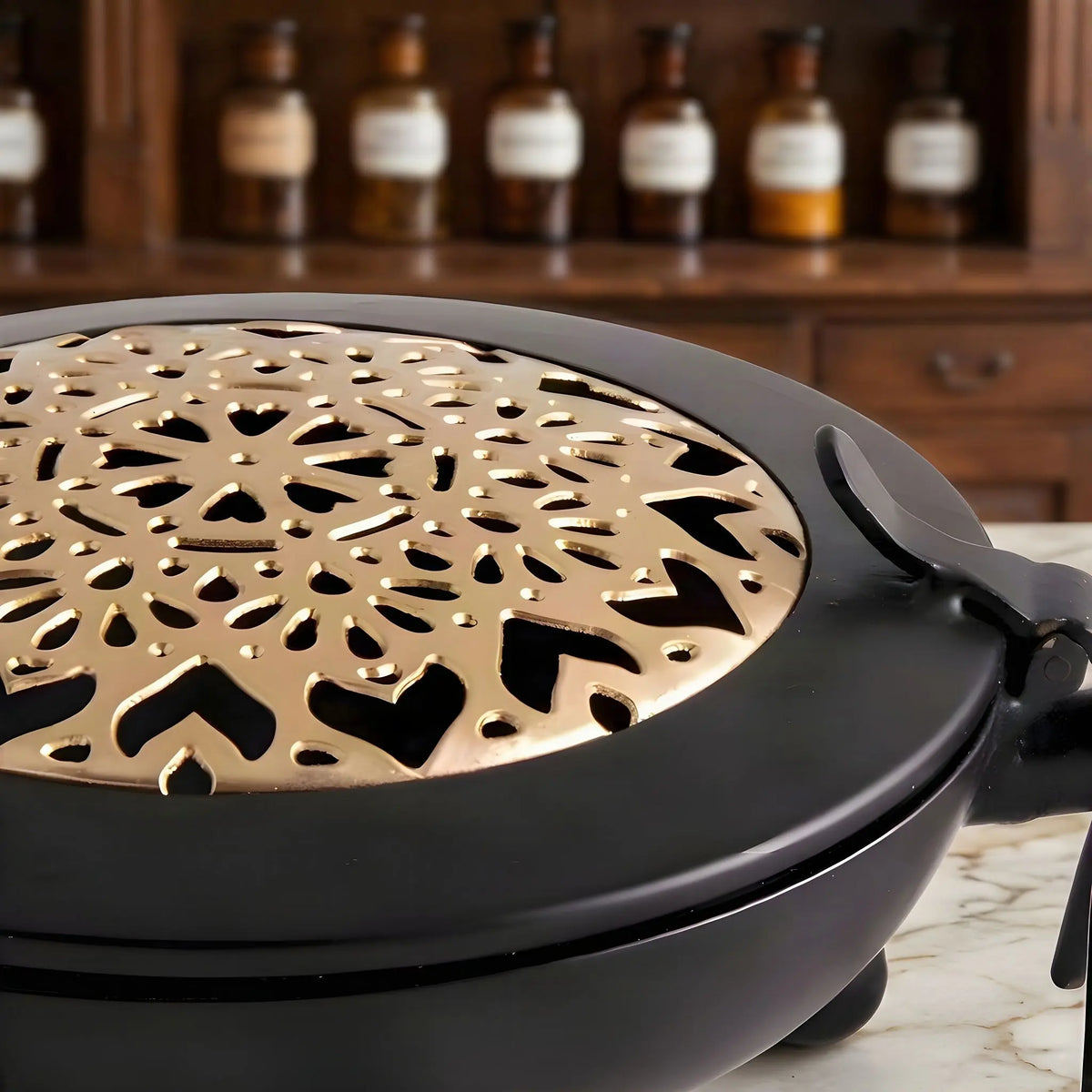 Das ausgestanzte Mandala auf der goldfarbenen Deckelscheibe aus der Nähe, auf Marmor vor einem Apothekerschrank