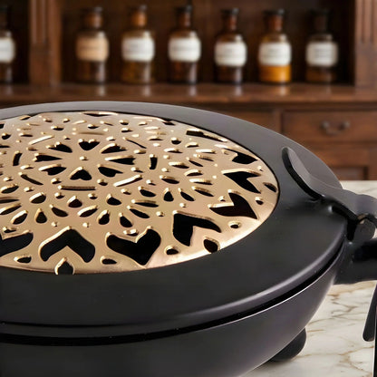 Das ausgestanzte Mandala auf der goldfarbenen Deckelscheibe aus der Nähe, auf Marmor vor einem Apothekerschrank