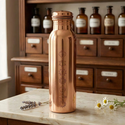 Polierte Kupfer-Trinkflasche mit 7-Chakren-Gravur auf Marmortheke vor Apothekerschrank – Spirit of Gaia