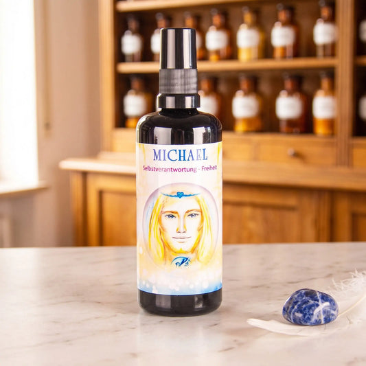 Seraphim Engel-Essenz Michael: Aura-Spray in dunkler Violettglasflasche auf Marmortheke vor Apothekerschrank, daneben ein Sodalith und eine weiße Feder – Spirit of Gaia
