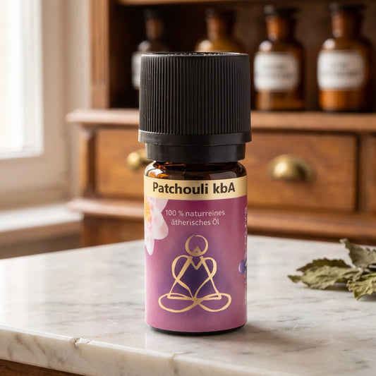 Ätherisches Öl Patchouli: Fläschchen aus Braunglas auf Marmortheke vor Apothekerschrank, daneben Patchouliblätter – Spirit of Gaia