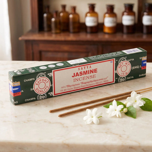 Satya Jasmine Räucherstäbchen: 15-g-Packung auf einer Marmortheke vor einem Apothekerschrank, daneben zwei lose Räucherstäbchen – Spirit of Gaia