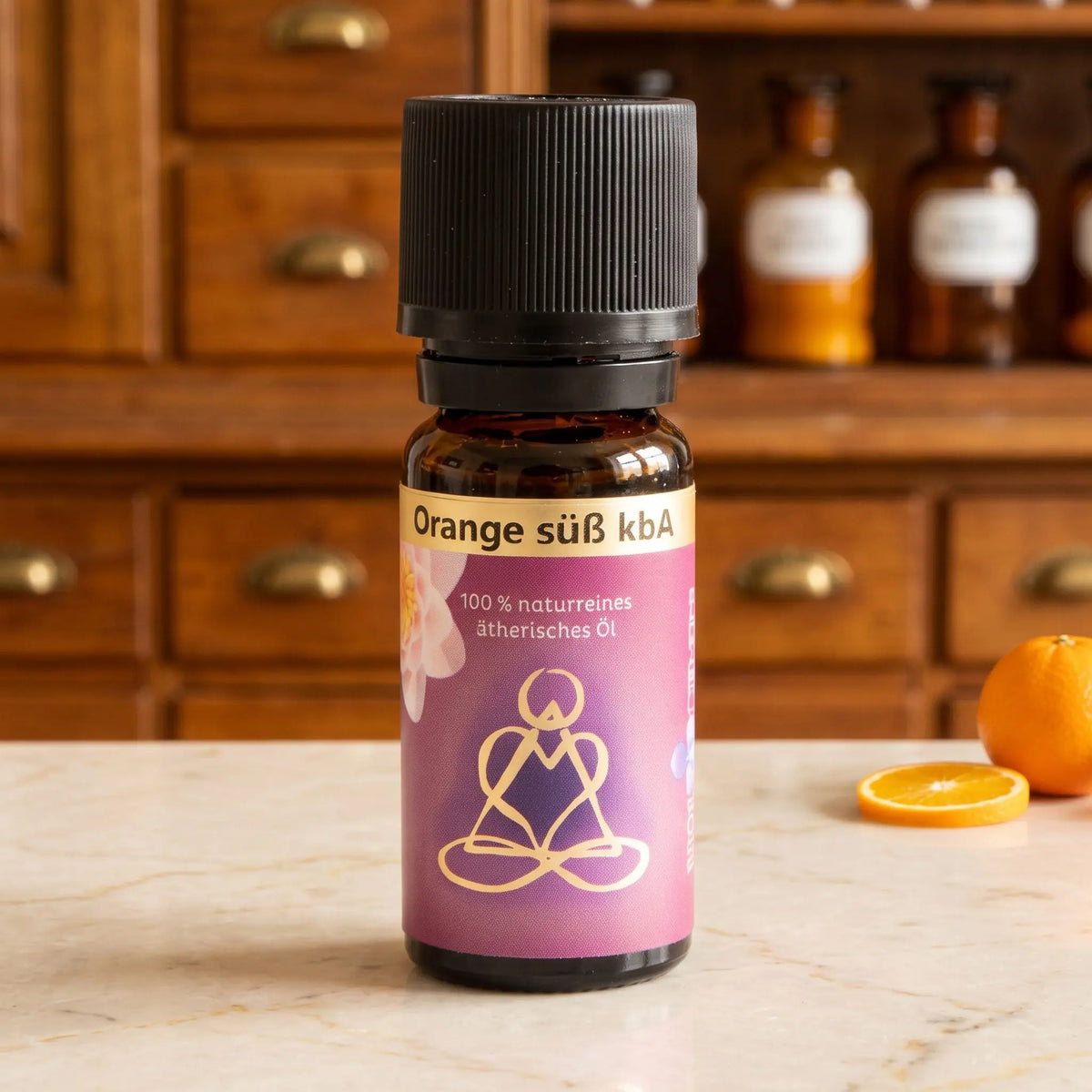 Ätherisches Öl Orange süß: Fläschchen aus Braunglas auf Marmortheke vor Apothekerschrank, daneben eine Orange – Spirit of Gaia