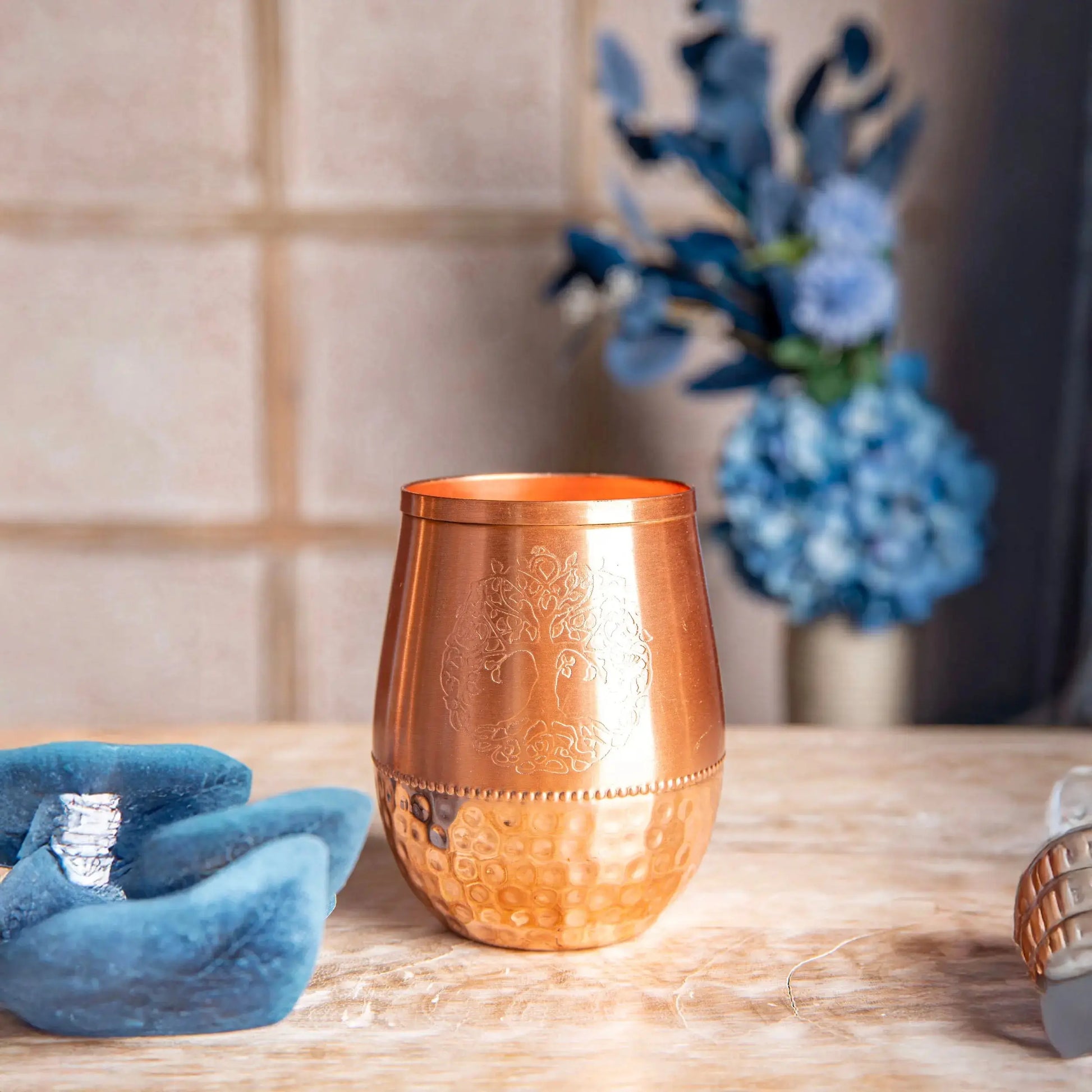 Kupfertrinkbecher mit eingraviertem Baum des Lebens Motiv, glattem oberen Rand und gehämmerter unterer Hälfte, auf einem Holztisch dekoriert
