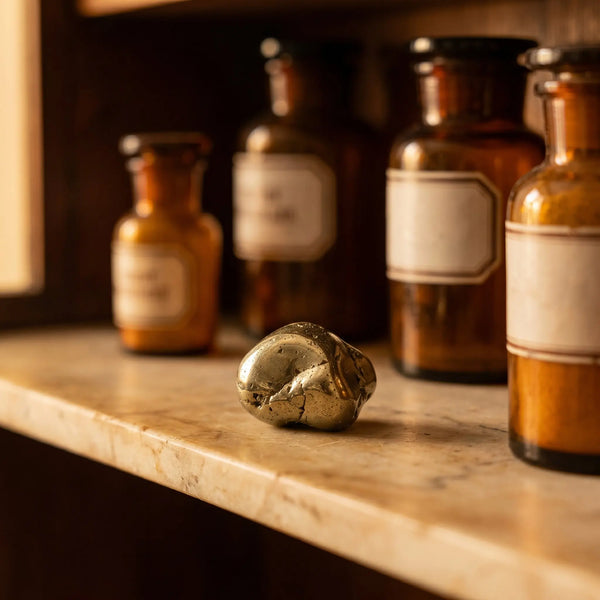 Pyrit Trommelstein – metallisch goldglänzender Heilstein (Katzengold) auf antiker Apotheker-Marmorablage