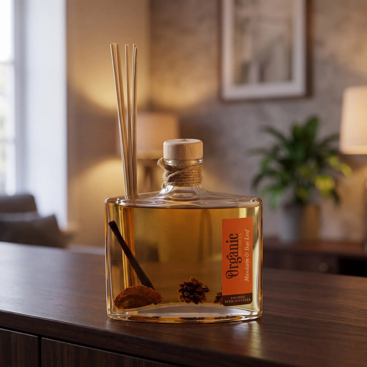 Reed Diffuser Mandarine und Lorbeerblatt am Abend auf einem Sideboard, die Schilfrohrstäbchen aufgefächert