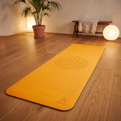 EcoBalance Yogamatte aus TPE, 182 × 61 cm, 6 mm, Blume des Lebens, orange/grau: ausgerollt auf dem Holzboden, in der Mitte die eingelaserte Blume des Lebens, warmes Abendlicht – Spirit of Gaia