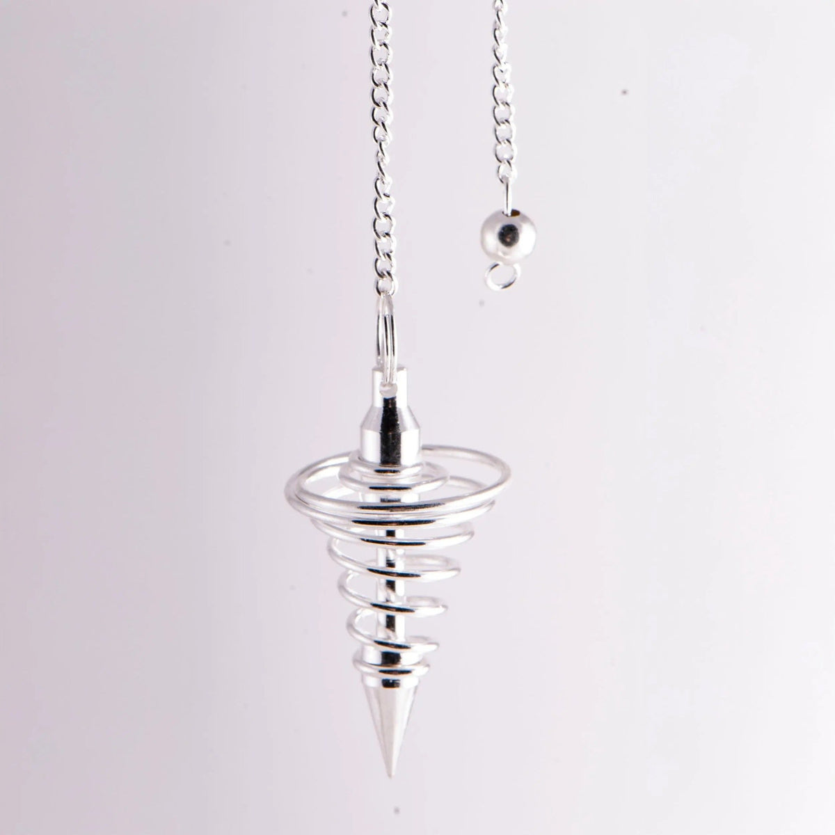 Spiralpendel aus versilbertem Messing, ca. 42 mm: hängend an der Kette vor hellem Grund