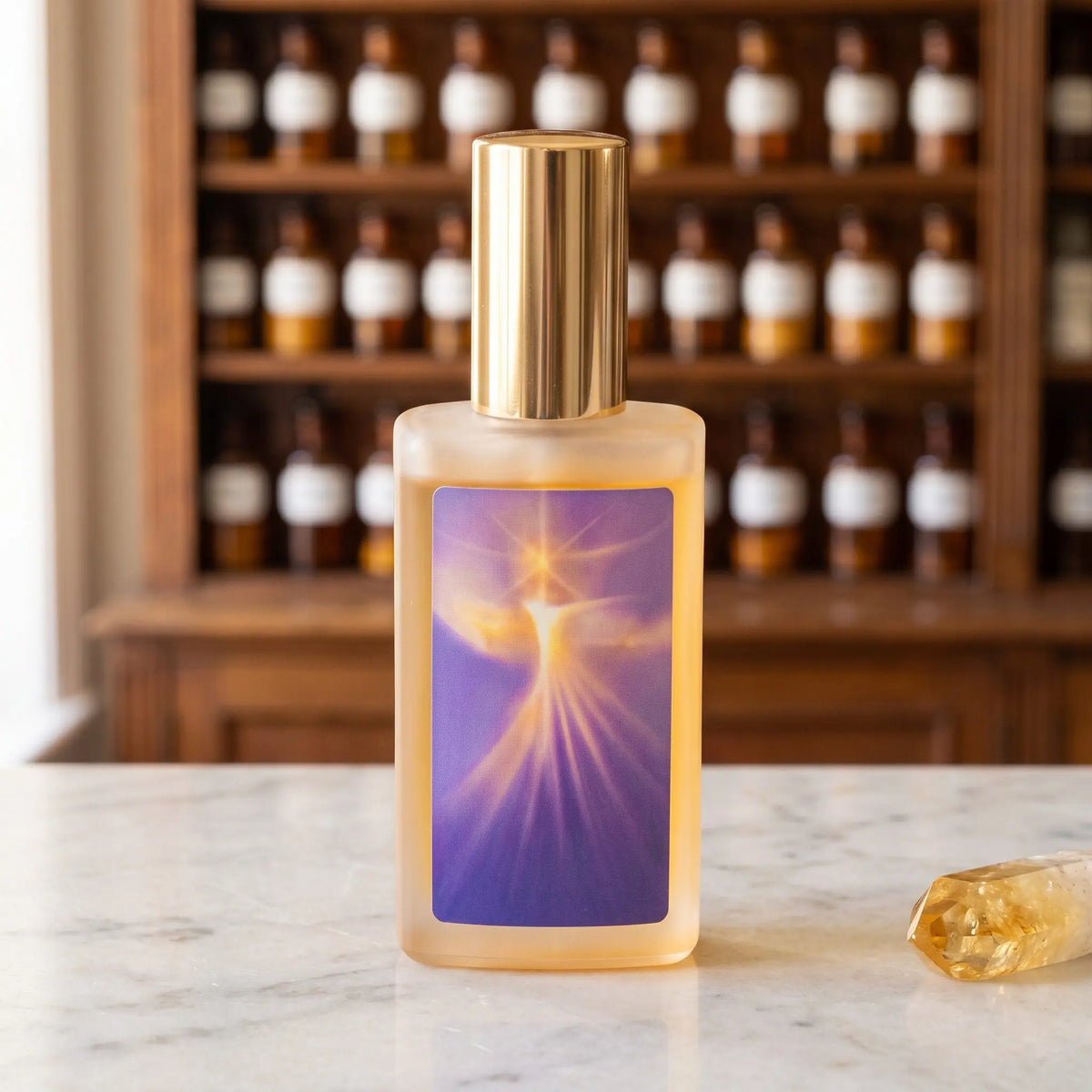 SeelenTor Goldene Essenz: Sprühflakon aus satiniertem Glas mit Bildetikett auf Marmortheke vor Apothekerschrank, daneben ein Citrin – Spirit of Gaia