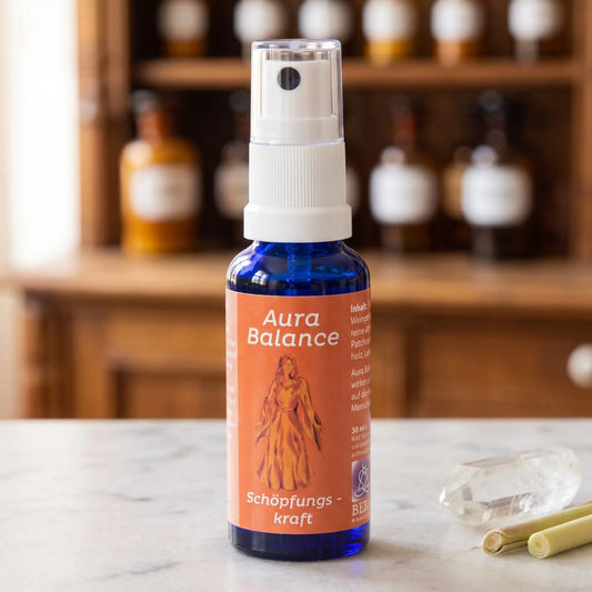 Energiespray Schöpfungskraft (Aura Balance): blaue Sprühflasche mit orangefarbenem Etikett auf Marmortheke vor Apothekerschrank, daneben ein Bergkristall und Zitronengras – Spirit of Gaia