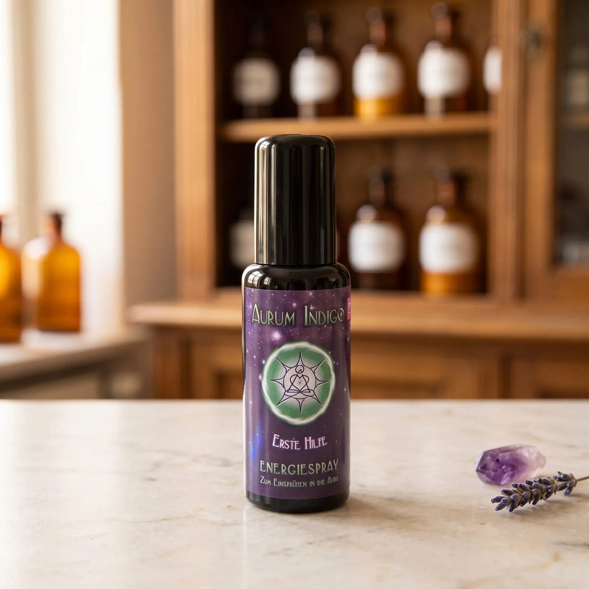 Energiespray Aurum Indigo Erste Hilfe: Sprühflasche aus Violettglas auf Marmortheke vor Apothekerschrank, daneben ein Amethyst und ein Lavendelzweig – Spirit of Gaia