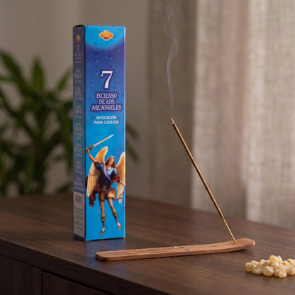 Räucherstäbchen 7 Erzengel: glimmendes Räucherstäbchen mit feinem Rauch im Holzhalter, dahinter die Packung, auf einem Sideboard am Abend