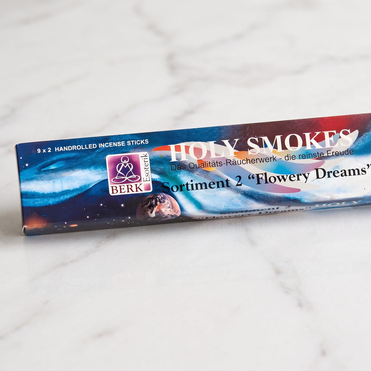 Nahaufnahme der Packung Flowering Dreams Sortiment 2 mit Holy-Smokes-Schriftzug, Berk-Esoterik-Logo und dem Aufdruck 9 x 2 Räucherstäbchen auf Marmor