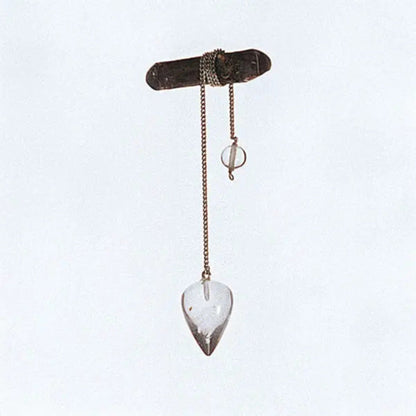 Bergkristall-Pendel mit Edelstahl-Panzerkette, Tropfen ca. 2,5 cm: hängend an einem Zweig vor hellem Grund
