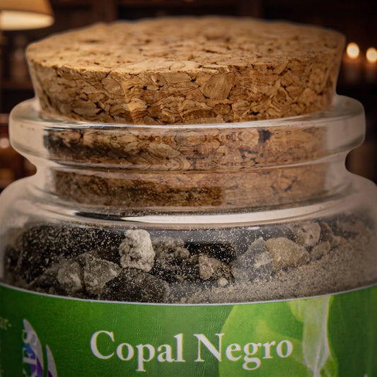 Copal Negro (Saumerio), reines Räucherharz von Berk, 60 ml im Korkglas: Nahaufnahme des Glases mit schwarzem Copal, Korken und Etikett vor der warmen, unscharfen Abendapotheke – Spirit of Gaia