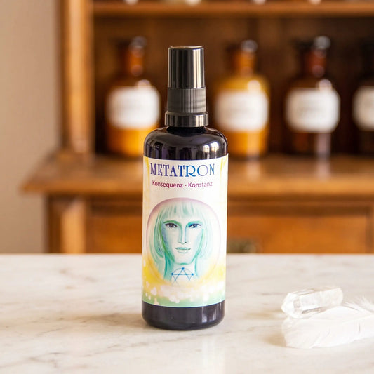 Seraphim Engel-Essenz Metatron: Aura-Spray in dunkler Violettglasflasche auf Marmortheke vor Apothekerschrank, daneben ein Bergkristall und eine weiße Feder – Spirit of Gaia