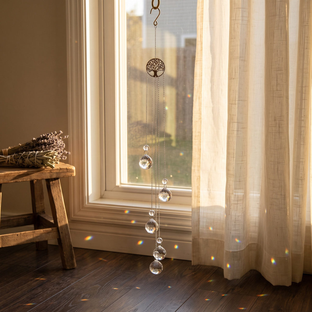 Yggdrasil Suncatcher am hohen Fenster mit Vorhang, Lichtpunkte in Regenbogenfarben auf dem Holzboden