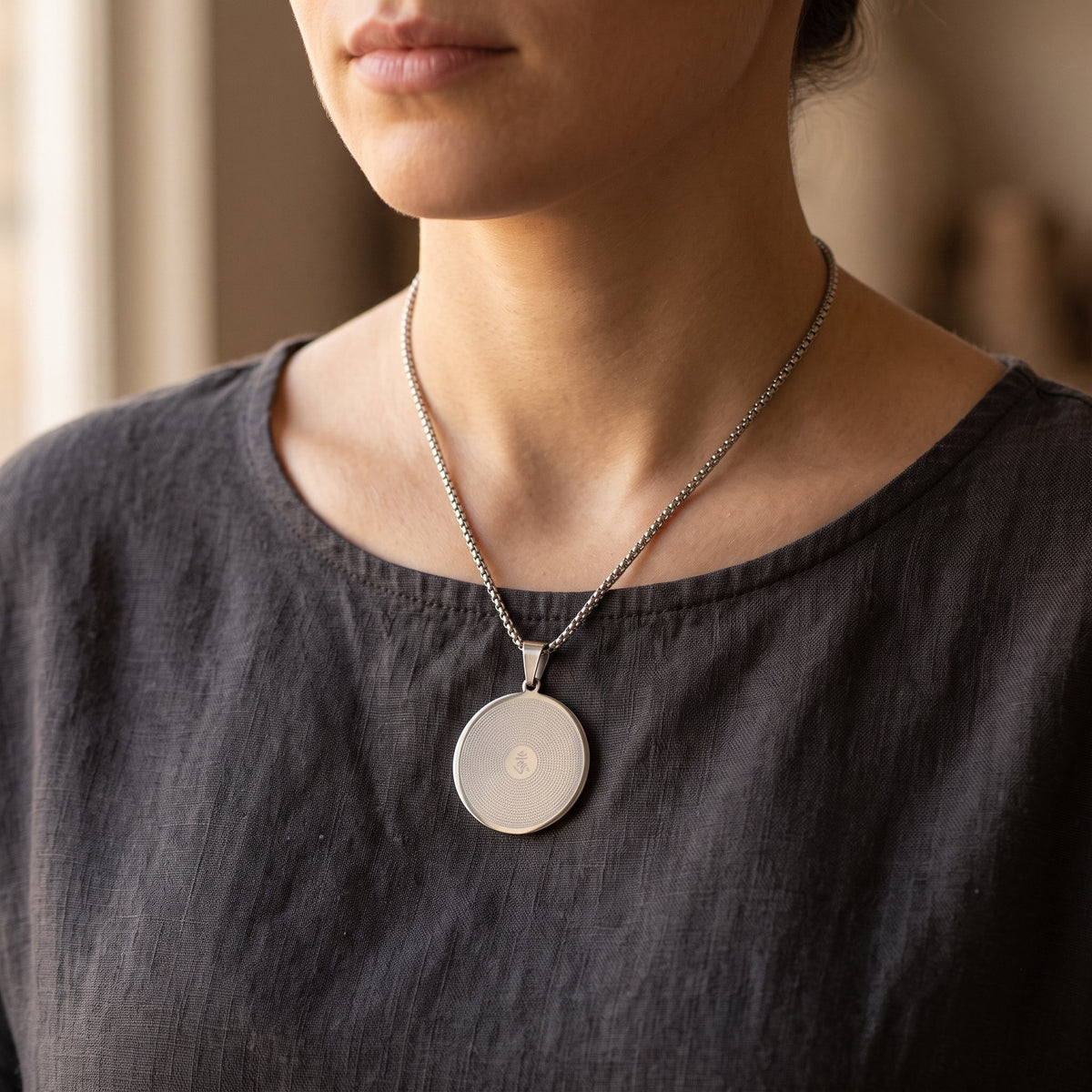 Mantra Anhänger mit OM an 60 cm Kette auf dem Brustbein, dunkles Leinenoberteil
