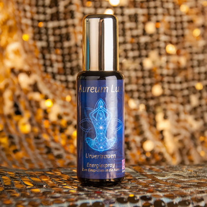 Energiespray Aureum Lux Urvertrauen, 50-ml-Sprühflasche aus Violettglas vor glitzerndem Hintergrund