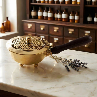 Messing-Räuchergefäß mit ausgestanzter Blume des Lebens im Klappdeckel auf einer Marmortheke vor einem Apothekerschrank