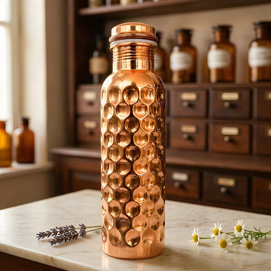 Facettiert gehämmerte, hochglanzpolierte Kupfer-Trinkflasche auf Marmortheke vor Apothekerschrank – Spirit of Gaia