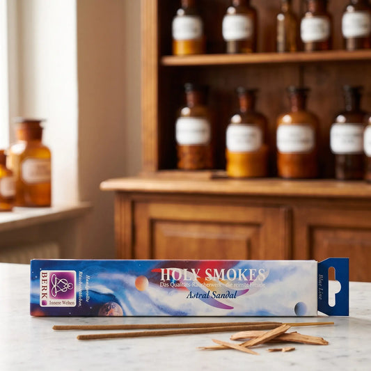 Astral Sandel Räucherstäbchen Blue Line: Packung auf einer Marmortheke vor einem Apothekerschrank, daneben zwei lose Räucherstäbchen und ein paar Sandelholzspäne – Spirit of Gaia