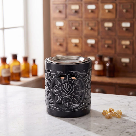 Räuchergefäß & Duftlampe Shakti – schwarzer Speckstein, inkl. Sieb & Aromaschale auf einer Marmortheke vor einem Apothekerschrank – Spirit of Gaia