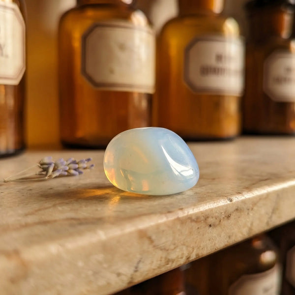 Opalith Trommelstein – milchig-schimmernder Heilstein (Opalglas) auf antiker Apotheker-Marmorablage