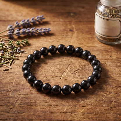 Schwarzer Turmalin Kugelarmband auf Holz neben getrocknetem Lavendel