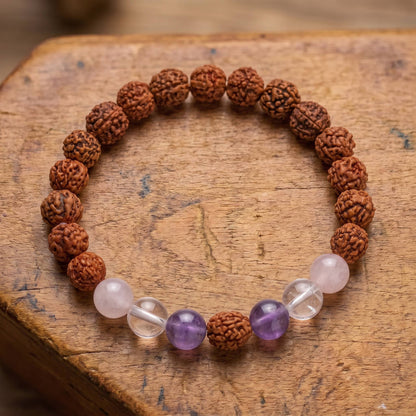 Draufsicht auf das Rudraksha Armband mit Edelsteinen auf altem Holz: Rosenquarz, Bergkristall und Amethyst um einen Rudraksha-Samen