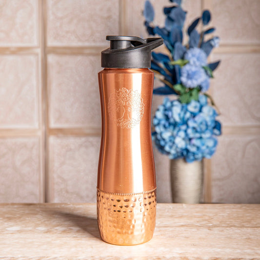Ergonomische Kupfertrinkflasche mit schwarzem Sportverschluss, eingraviertem Baum des Lebens auf glatter oberer Hälfte und gehämmerter Struktur unten.
