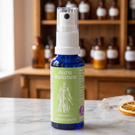 Energiespray Seelenschwingung (Aura Balance): blaue Sprühflasche mit hellgrünem Etikett auf Marmortheke vor Apothekerschrank, daneben ein Bergkristall und eine getrocknete Orangenscheibe – Spirit of Gaia