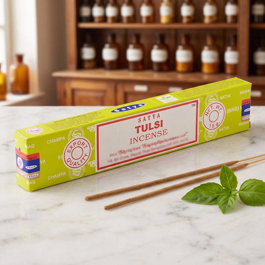 Satya Tulsi Räucherstäbchen: 15-g-Packung auf einer Marmortheke vor einem Apothekerschrank, daneben zwei lose Räucherstäbchen – Spirit of Gaia