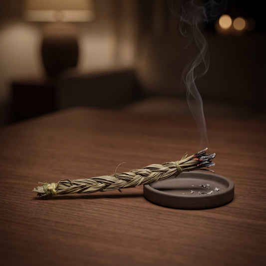 Sweetgrass-Zopf (Süßgras): das Zopfende glimmt über einer flachen Keramikschale, feiner Rauch steigt am Abend auf – Spirit of Gaia