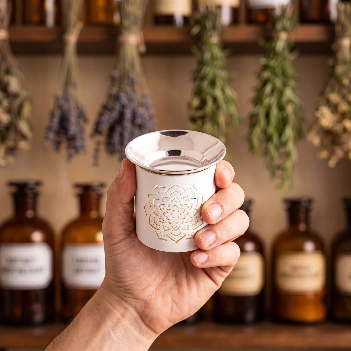 Weißes Räucherstövchen aus Eisen mit erhabenem Mandala und flacher Edelstahlschale – Groessenvergleich in der Hand