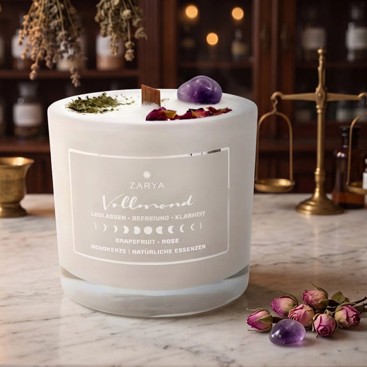 Zeremonie Kerze Vollmond mit Amethyst, Duft Grapefruit und Rose: Kerze im Glas auf der Marmortheke einer alten Apotheke am Abend, daneben ein paar getrocknete Rosenknospen und ein Amethyst – Spirit of Gaia