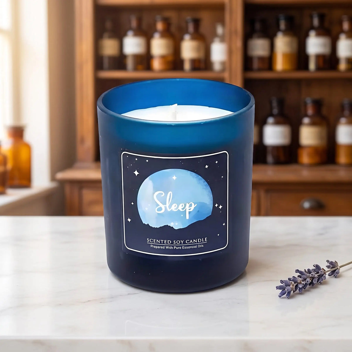 Duftkerze Sleep im Glas von Song of India: Sojawachskerze im dunkelblauen Glas auf Marmortheke vor Apothekerschrank, daneben ein Lavendelzweig – Spirit of Gaia