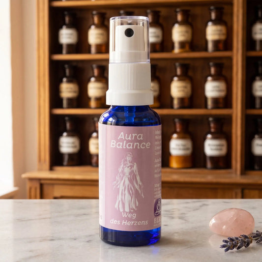 Energiespray Weg des Herzens (Aura Balance): blaue Sprühflasche mit rosafarbenem Etikett auf Marmortheke vor Apothekerschrank, daneben ein Rosenquarz und ein Lavendelzweig – Spirit of Gaia