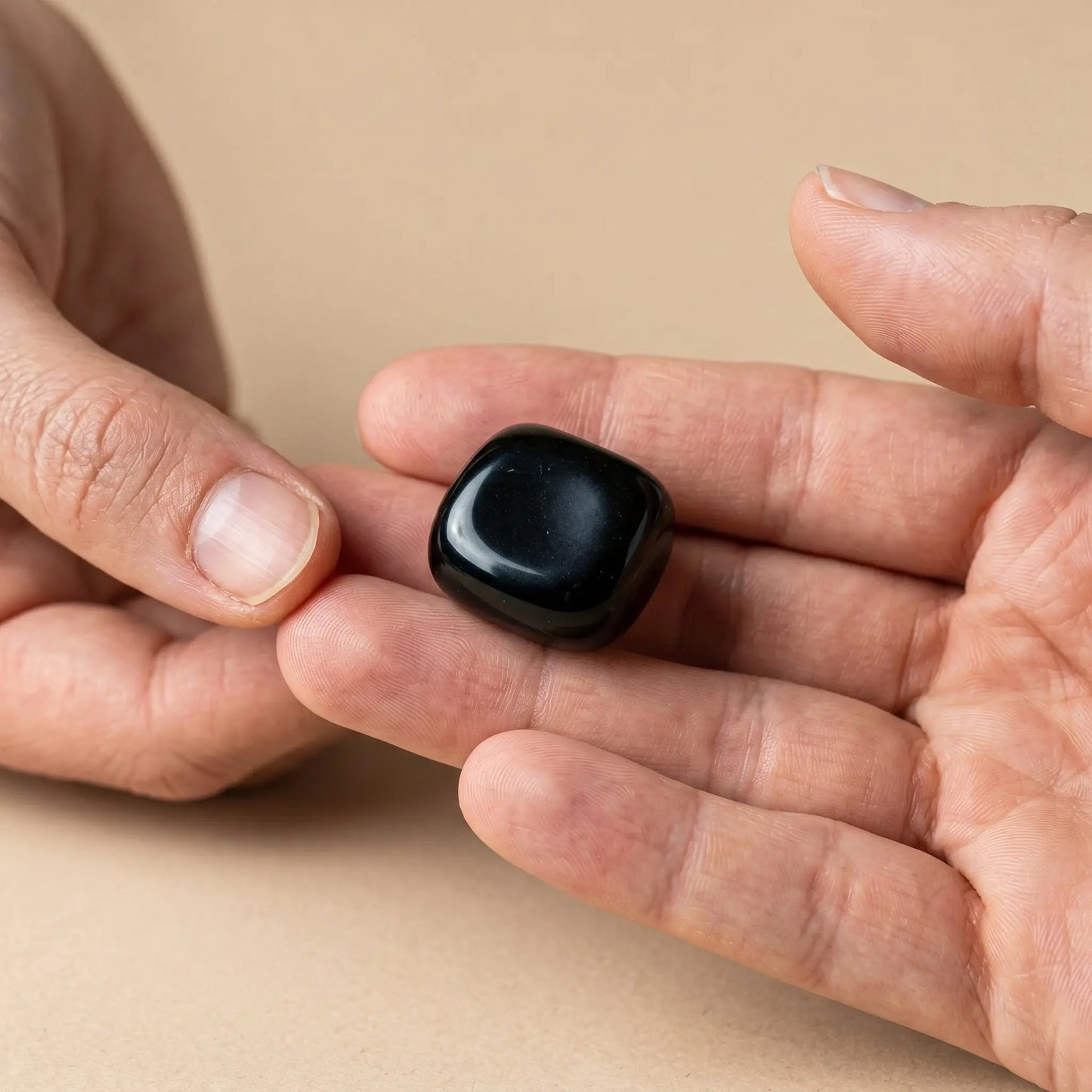 Onyx Trommelstein – Größenvergleich in der Hand, ca. 2–3 cm