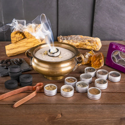 Räucherharze auf glühender Kohle in einer Messingschale mit aufsteigendem Rauch, Palo Santo und geöffneten Döschen